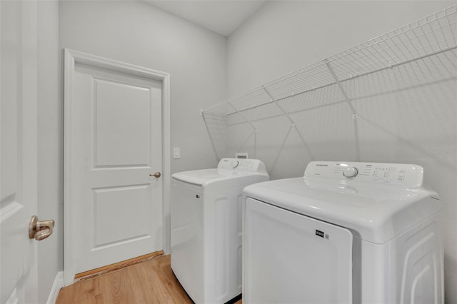 laundry area with separate washer and dryer and light hardwood / wood-style flooring