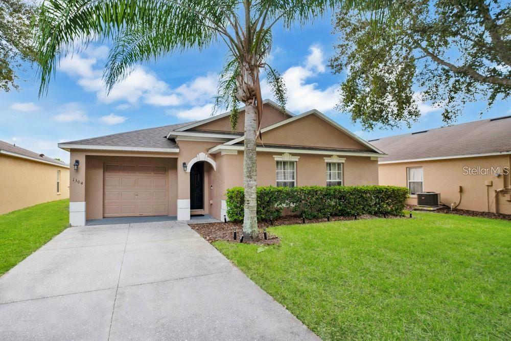 ranch-style house featuring central AC unit, a garage, and a front lawn