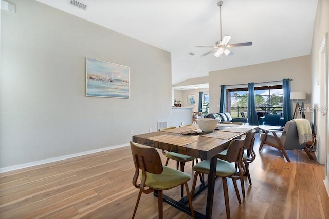 dining space with ceiling fan, light wood-type flooring, and a towering ceiling