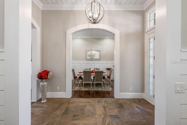 foyer with a notable chandelier, baseboards, and crown molding