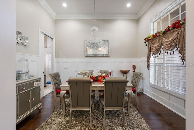 dining area featuring wainscoting, ornamental molding, dark wood-type flooring, a chandelier, and a decorative wall