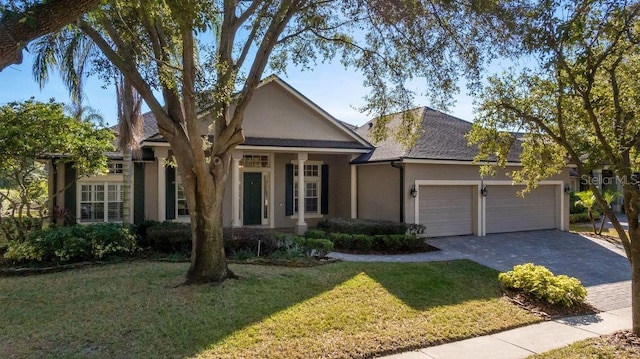 ranch-style house featuring a front lawn, decorative driveway, an attached garage, and stucco siding