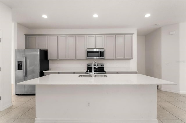 kitchen with light stone countertops, appliances with stainless steel finishes, and a center island with sink