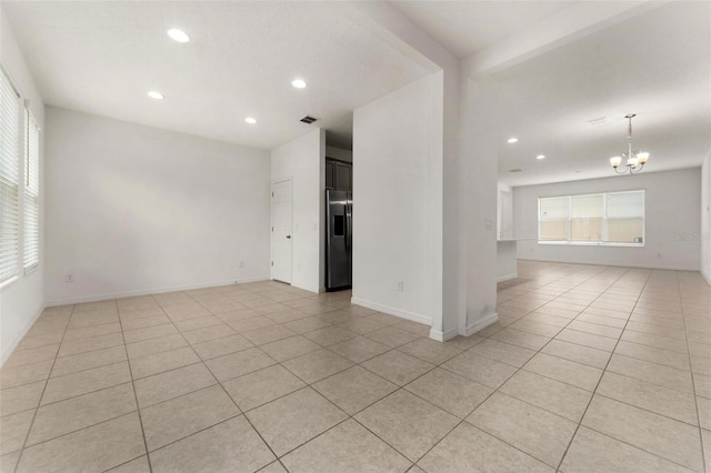 empty room featuring light tile patterned floors and an inviting chandelier