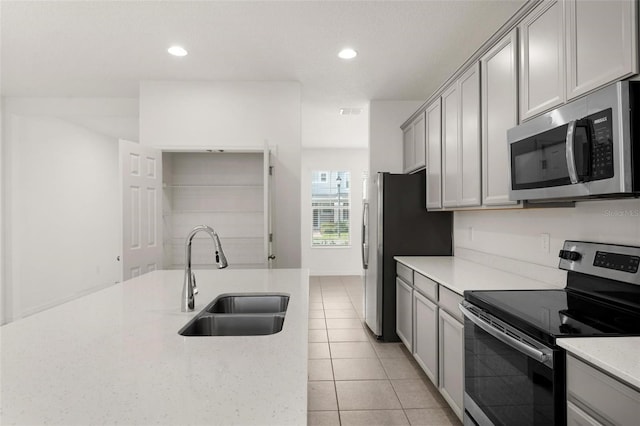 kitchen with light stone countertops, gray cabinetry, stainless steel appliances, sink, and light tile patterned flooring