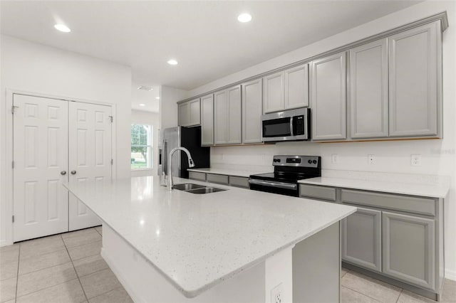 kitchen featuring appliances with stainless steel finishes, gray cabinets, and a kitchen island with sink