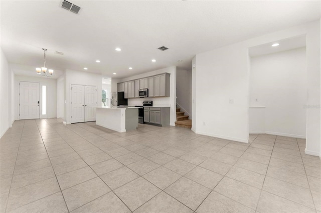 kitchen featuring gray cabinetry, a center island with sink, decorative light fixtures, light tile patterned flooring, and stainless steel appliances