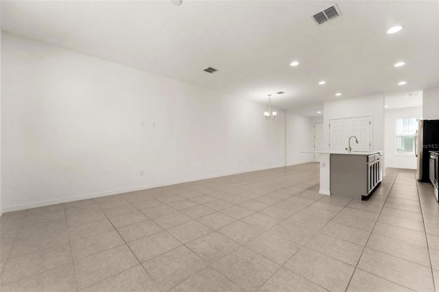 unfurnished room featuring sink, light tile patterned flooring, and an inviting chandelier