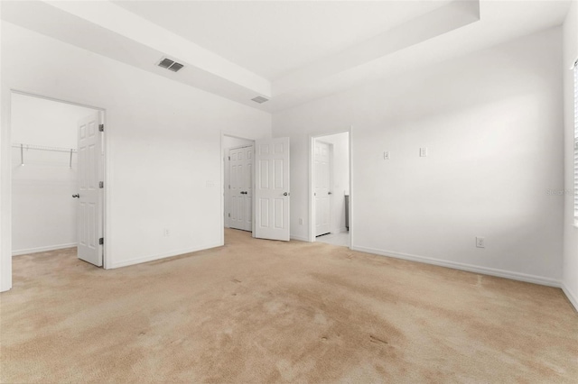 unfurnished bedroom featuring light colored carpet, a spacious closet, and a closet