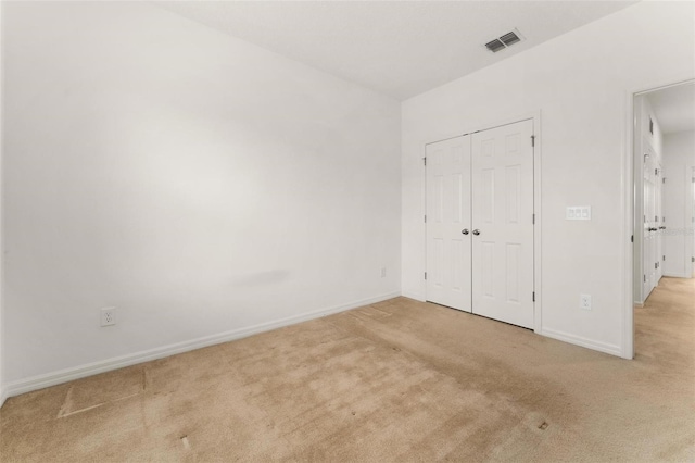 unfurnished bedroom with a closet and light colored carpet