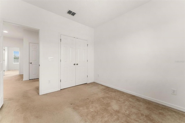 unfurnished bedroom featuring a closet and light colored carpet