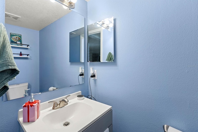 bathroom with vanity, a textured ceiling, and toilet