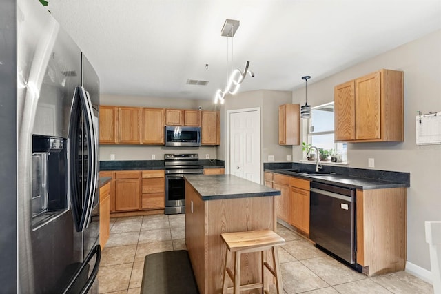 kitchen featuring a breakfast bar, a center island, sink, appliances with stainless steel finishes, and decorative light fixtures