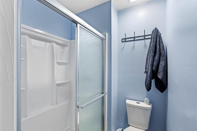 bathroom featuring toilet and an enclosed shower