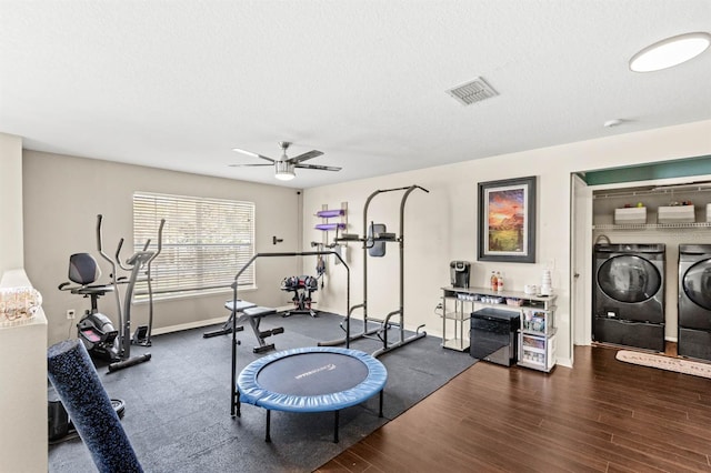 exercise room featuring ceiling fan, washing machine and dryer, dark hardwood / wood-style floors, and a textured ceiling