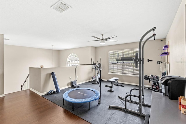 exercise room with a textured ceiling, ceiling fan, and wood-type flooring