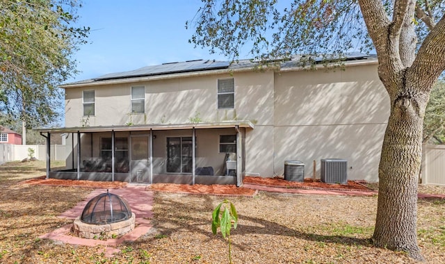 back of house with cooling unit, an outdoor fire pit, and a sunroom