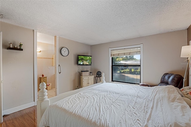 bedroom with hardwood / wood-style floors, a textured ceiling, and connected bathroom