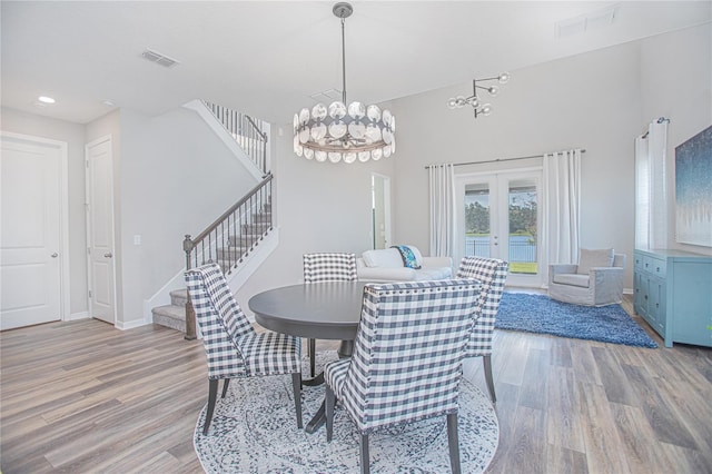 dining space with a chandelier, french doors, and light hardwood / wood-style floors