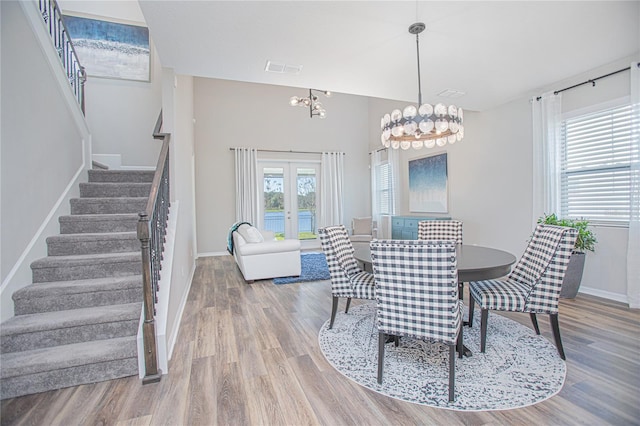 dining area with french doors, hardwood / wood-style flooring, and a notable chandelier