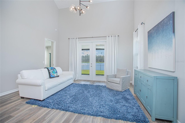 living room with french doors, an inviting chandelier, high vaulted ceiling, and hardwood / wood-style flooring