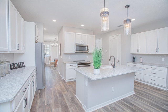 kitchen with appliances with stainless steel finishes, sink, pendant lighting, light hardwood / wood-style flooring, and white cabinetry