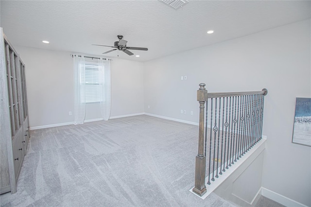 carpeted empty room featuring ceiling fan and a textured ceiling