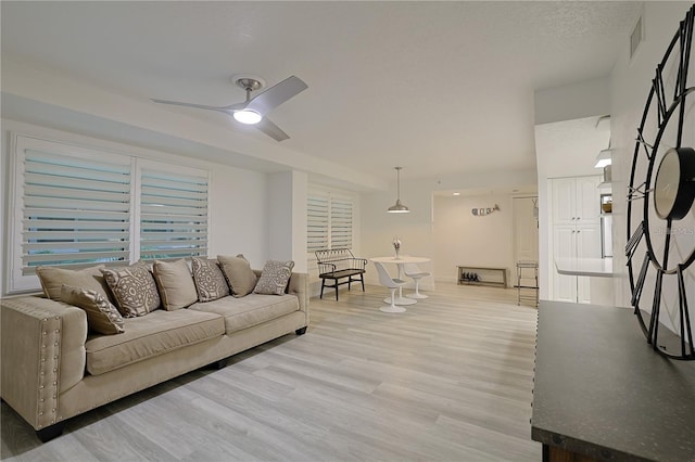 living room featuring a textured ceiling, light hardwood / wood-style flooring, and ceiling fan