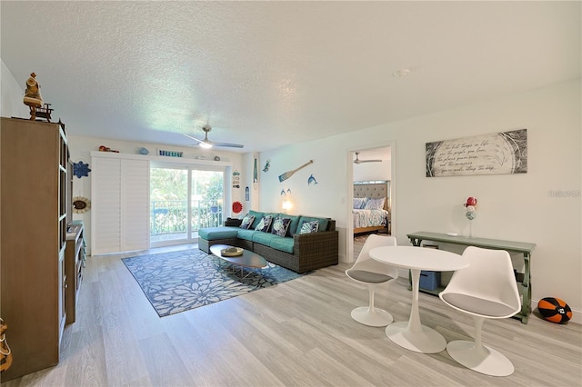 living room featuring ceiling fan, a textured ceiling, and light hardwood / wood-style floors