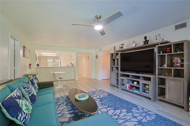 living room featuring ceiling fan, a textured ceiling, and light wood-type flooring