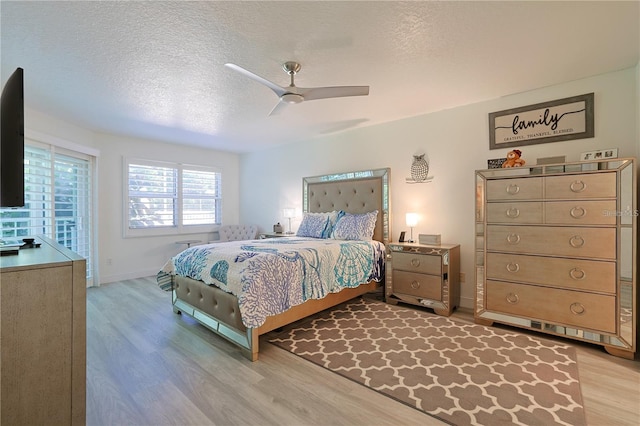 bedroom with ceiling fan, a textured ceiling, and light hardwood / wood-style floors