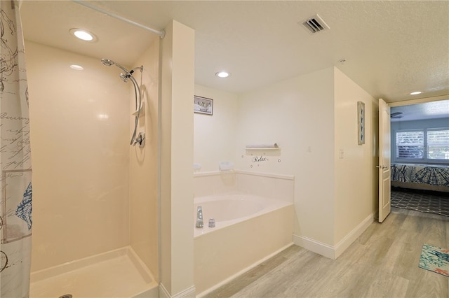 bathroom with shower with separate bathtub, hardwood / wood-style floors, and a textured ceiling