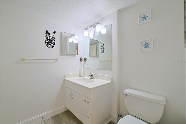 bathroom with vanity, toilet, hardwood / wood-style floors, and a textured ceiling