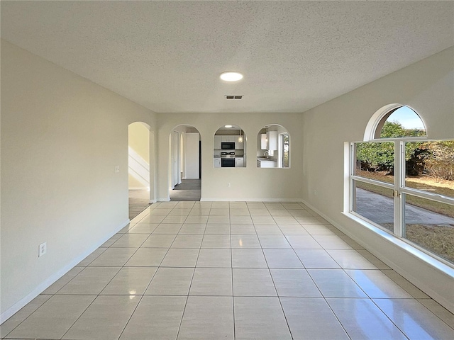 empty room featuring a textured ceiling and light tile patterned flooring