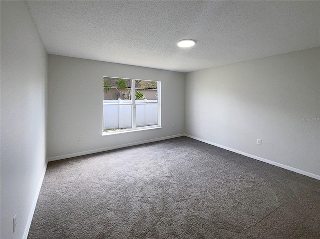 unfurnished room with dark colored carpet and a textured ceiling