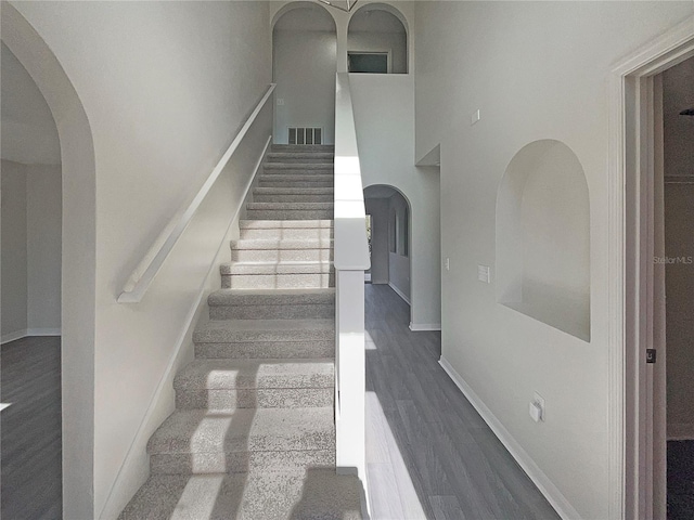 stairs featuring hardwood / wood-style floors and a towering ceiling