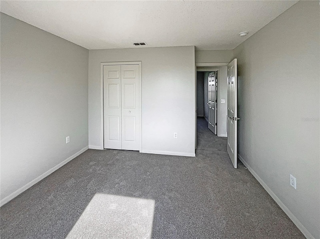 unfurnished bedroom with dark colored carpet and a closet