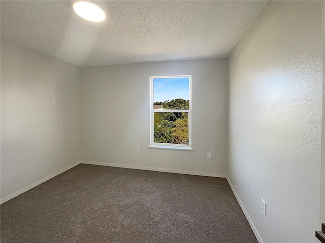 unfurnished room with a textured ceiling and dark colored carpet