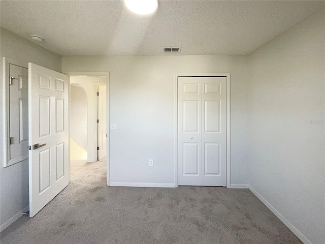 unfurnished bedroom featuring a closet, light colored carpet, and a textured ceiling