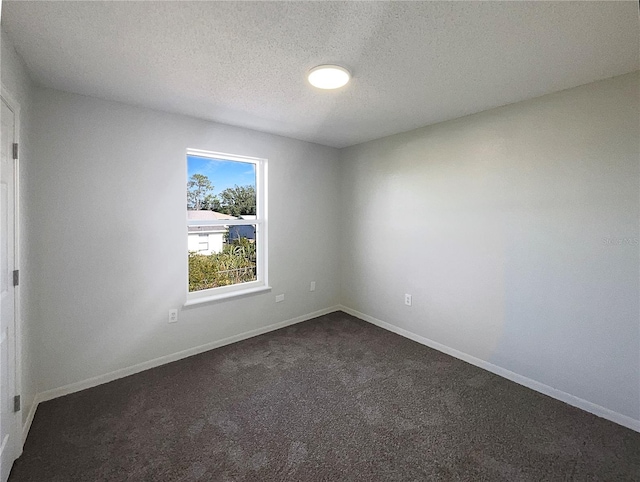 spare room with dark carpet and a textured ceiling