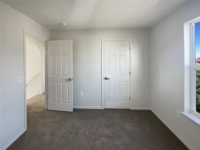 unfurnished bedroom featuring dark carpet and a textured ceiling