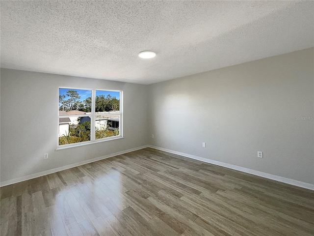 spare room with a textured ceiling and dark wood-type flooring