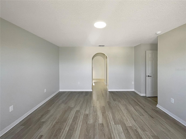 unfurnished room featuring dark wood-type flooring and a textured ceiling