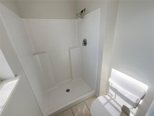 bathroom featuring toilet, a shower, and tile patterned floors