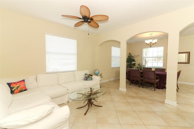 tiled living room with ceiling fan with notable chandelier