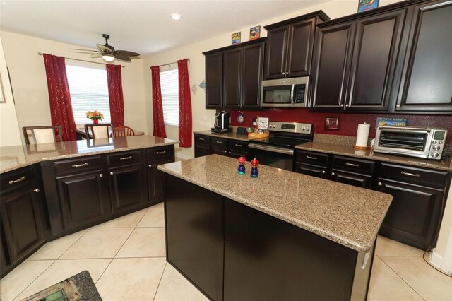 kitchen with ceiling fan, a center island, light tile patterned floors, and stainless steel appliances