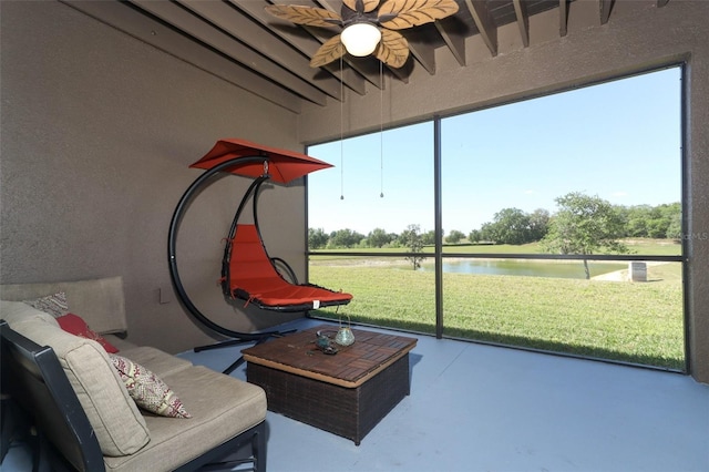 sunroom / solarium featuring ceiling fan and a water view