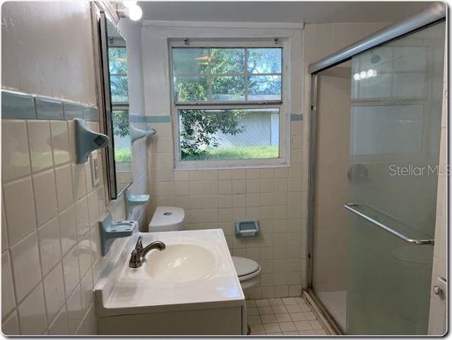 bathroom with plenty of natural light, a shower with shower door, and tile walls