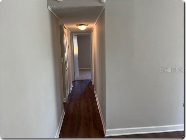 hallway with a textured ceiling, dark hardwood / wood-style floors, and crown molding