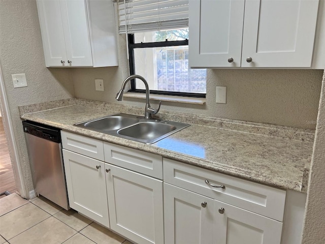 kitchen with dishwasher, white cabinetry, sink, and light tile patterned floors